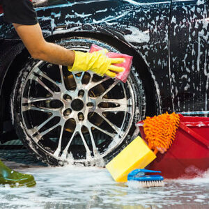 Male worker at car wash service washing a car.